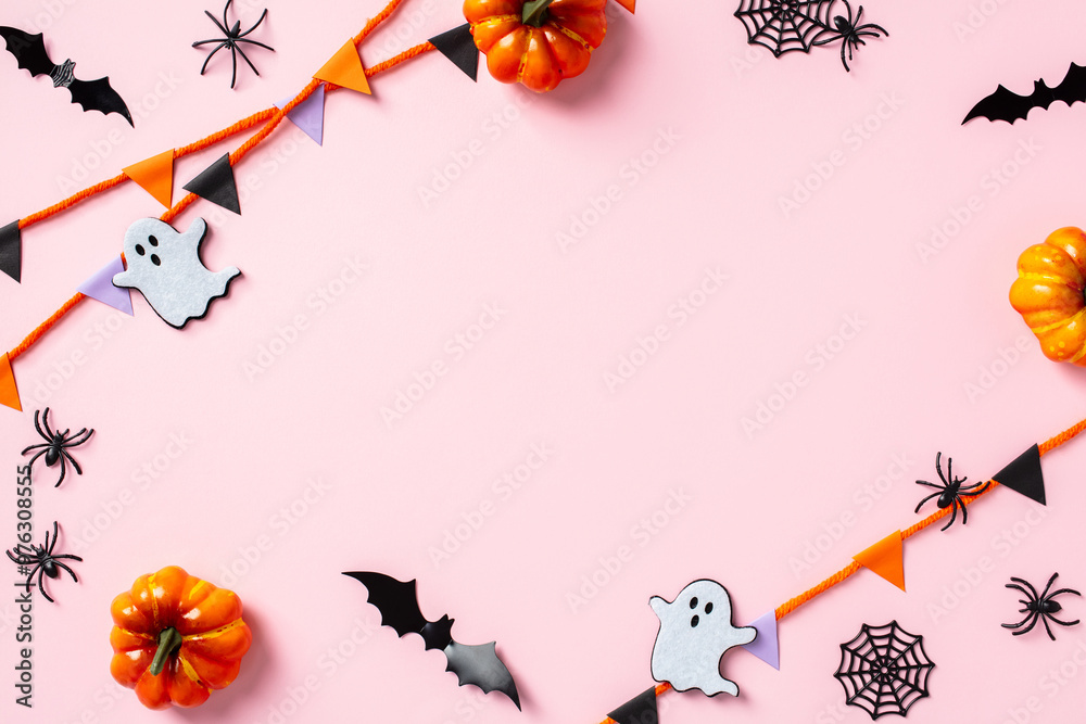 Fototapeta premium Frame of Halloween decorations on pastel pink background. Halloween concept. Flat lay, top view, copy space
