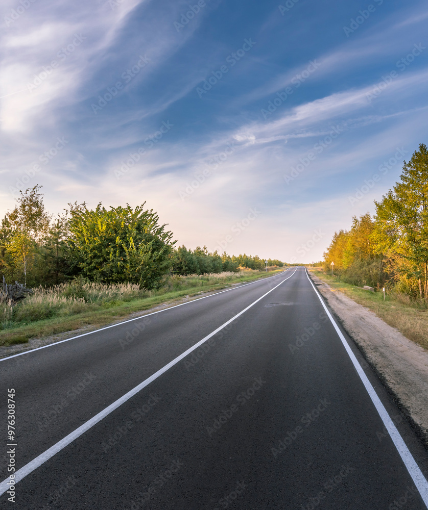 A long, empty road with a blue sky in the background A long, empty road with a blue sky in the background