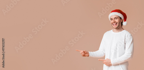 Christmas offer. Happy interracial couple pointing fingers at copy space in the middle of yellow studio background, panorama