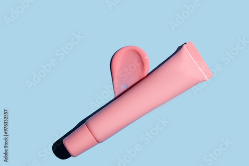 pink lip tint texture, cosmetics beauty product texture, liquid blush, lipstick, lip gloss swatches, package tube on blue photo