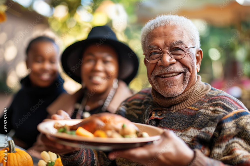 Elderly black man holding a plate with roasted turkey, with his family blurred in the background, everyone smiling and enjoying the festive atmosphere outdoors. Elderly black man holding a plate with roasted turkey, with his family blurred in the background, everyone smiling and enjoying the festive atmosphere outdoors.