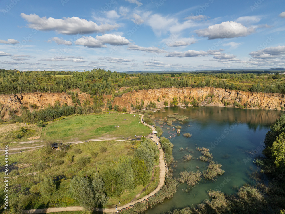 Naklejka premium Aerial drone photo of Quarry turquiose lake colour, open pit mining in Park Grodek, Jaworzno. Poland. Turquiose Water and Wooden Bridge on lake. Polish Maldives Park Grodek in Jaworzno from drone.