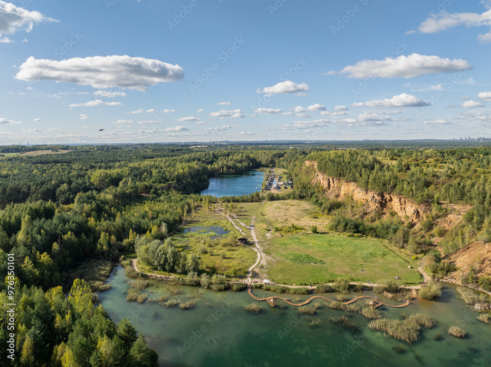 Fototapeta premium Aerial drone photo of Quarry turquiose lake colour, open pit mining in Park Grodek, Jaworzno. Poland. Turquiose Water and Wooden Bridge on lake. Polish Maldives Park Grodek in Jaworzno from drone.