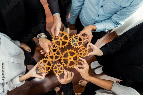 Group of multiracial business people joining gear wheels together as effective unity and productive teamwork concept. Efficient system business team process for solution solving. Meticulous