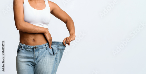 Картината върху платно Cropped of afro woman wearing too large jeans, demonstrating weight loss, effect