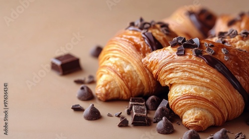 Freshly baked chocolate-filled croissants on a warm beige background showcasi...