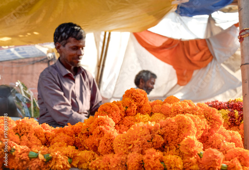 Florist seller at flower market smiling with orange flowers in India
