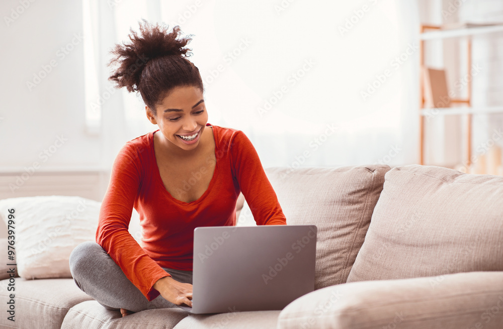Cheerful Black Lady Using Laptop Browsing Internet Sitting On Sofa At Home. Empty Space, Selective Focus Cheerful Black Lady Using Laptop Browsing Internet Sitting On Sofa At Home. Empty Space, Selective Focus
