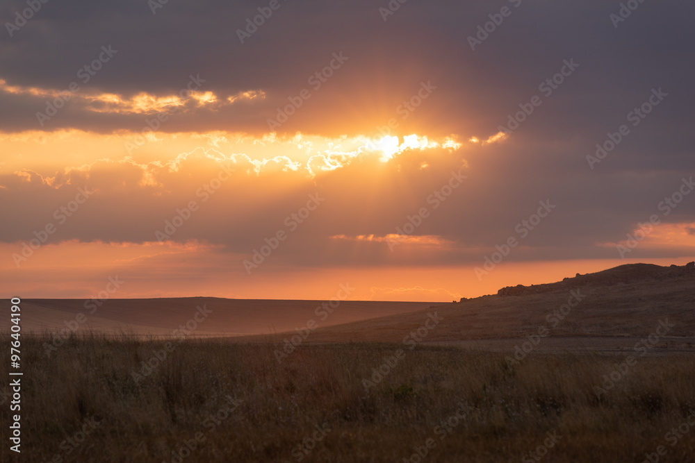The setting sun through the clouds and reflections on the hills The setting sun through the clouds and reflections on the hills