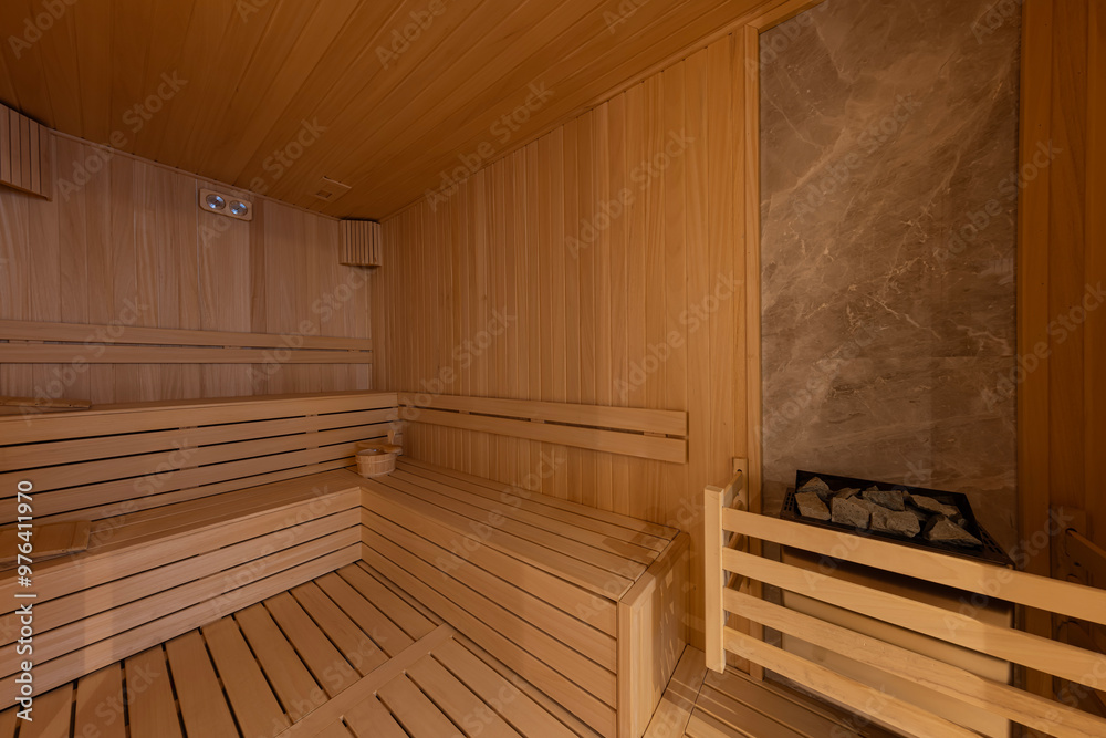 Interior of the Finnish sauna, classic wooden sauna with hot steam. Sauna room at hotel SPA center. Wooden interior baths, wooden benches and sun loungers sauna accessories, spa complex. Interior of the Finnish sauna, classic wooden sauna with hot steam. Sauna room at hotel SPA center. Wooden interior baths, wooden benches and sun loungers sauna accessories, spa complex.