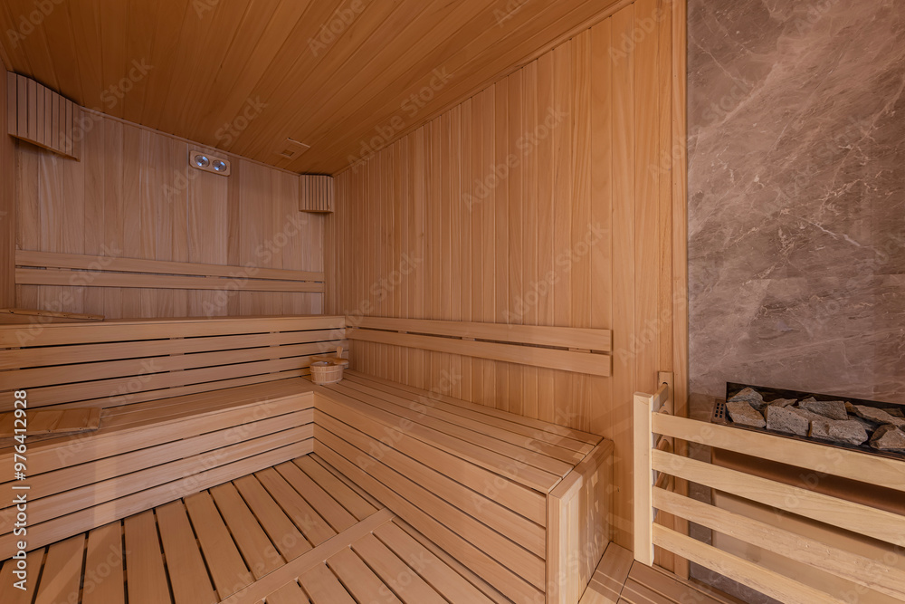 Interior of the Finnish sauna, classic wooden sauna with hot steam. Sauna room at hotel SPA center. Wooden interior baths, wooden benches and sun loungers sauna accessories, spa complex. Interior of the Finnish sauna, classic wooden sauna with hot steam. Sauna room at hotel SPA center. Wooden interior baths, wooden benches and sun loungers sauna accessories, spa complex.