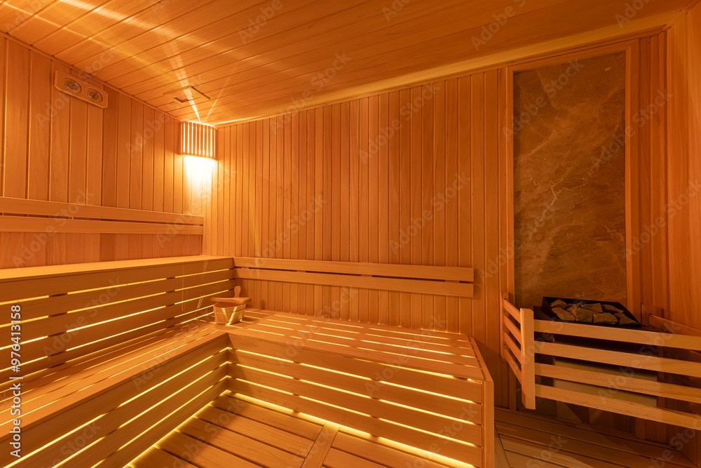 Interior of the Finnish sauna, classic wooden sauna with hot steam. Sauna room at hotel SPA center. Wooden interior baths, wooden benches and sun loungers sauna accessories, spa complex. Interior of the Finnish sauna, classic wooden sauna with hot steam. Sauna room at hotel SPA center. Wooden interior baths, wooden benches and sun loungers sauna accessories, spa complex.