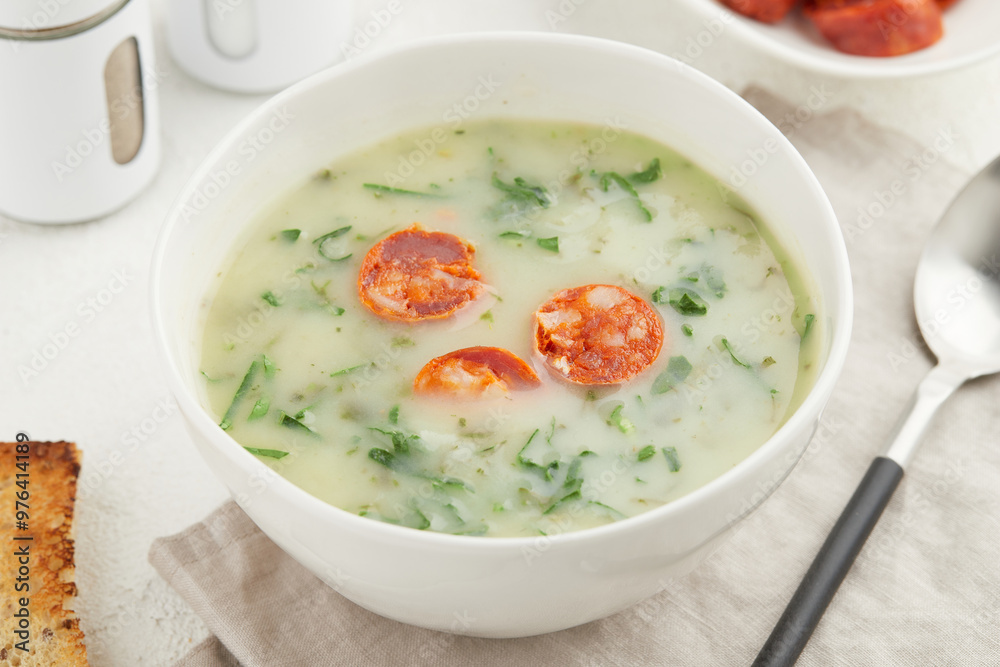 Typical Portuguese soup Caldo Verde with bread and chorizo sausage on white background close up Typical Portuguese soup Caldo Verde with bread and chorizo sausage on white background close up