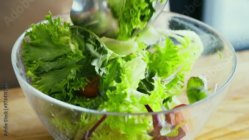 Preparing healthy snack. Woman mixing fresh vegetable salad with two spoons, close up