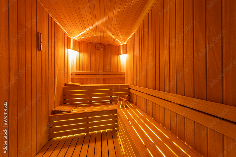 Interior of the Finnish sauna, classic wooden sauna with hot steam. Sauna room at hotel SPA center. Wooden interior baths, wooden benches and sun loungers sauna accessories, spa complex. Interior of the Finnish sauna, classic wooden sauna with hot steam. Sauna room at hotel SPA center. Wooden interior baths, wooden benches and sun loungers sauna accessories, spa complex.