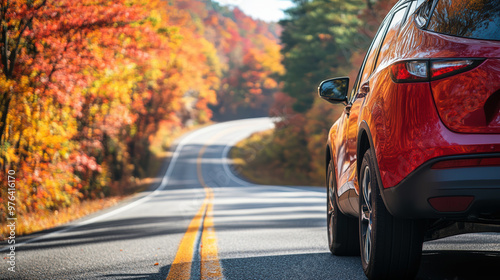 Obraz na płótnie Red car drives down a winding road, flanked by vibrant autumn foliage under a clear sky, capturing the essence of a serene road trip. w salonie