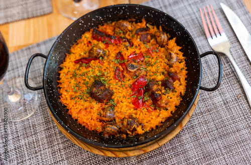 Appetizing traditional Valencian rice paella with snails served on platter photo