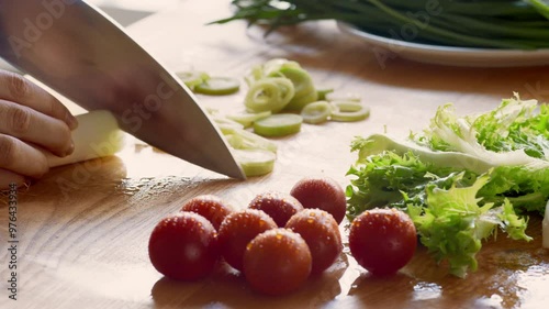 Woman preparing vegetarian salad, cutting fresh vegetables on kitchen table, close up