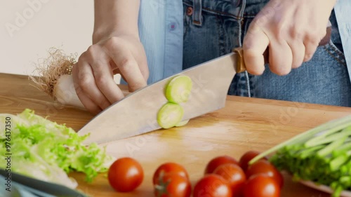 Vegetarian lifestyle. Woman slicing fresh green leek for healthy vegetable salad