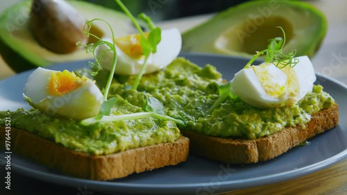 Trendy meal. Breakfast toasts with boiled egg, avocado and microgreens on plate, close up