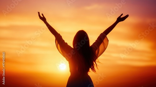 A silhoetted woman with arms raised, celebrating the beauty of a vibrant sunset, symbolizing freedom and joy.