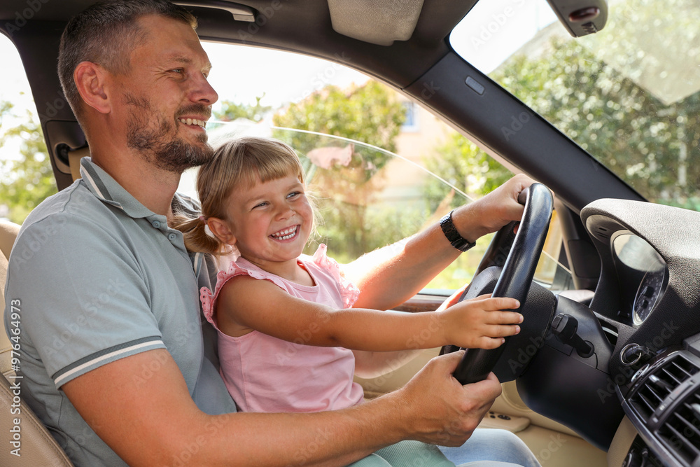 Happy man with his daughter holding steering wheel inside car Happy man with his daughter holding steering wheel inside car