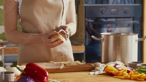 Close up of woman peeling potatoes with special tool at kitchen