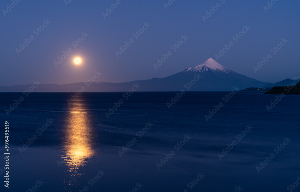 Full moon rising and reflecting on Lake Llanquihue after sunset, with the majestic Osorno Volcano in the background, viewed from Puerto Varas in the Patagonia of Chile. Full moon rising and reflecting on Lake Llanquihue after sunset, with the majestic Osorno Volcano in the background, viewed from Puerto Varas in the Patagonia of Chile.