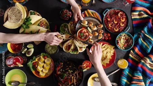 Mexican Food Fiesta. Family and friends around the table together. Corn, tortilla chips, cheese, tacos, salsa, chilies, and beef dishes