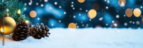 A festive image showcasing Christmas ornaments and pinecones nestled on a snow-covered surface with warm, glowing lights in the background, evoking holiday cheer and warmth. photo