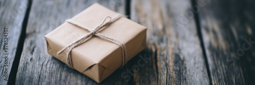 A neatly wrapped package tied with string, resting on rustic wooden planks, evokes a sense of simplicity, nostalgia and attention to detail in gifting.