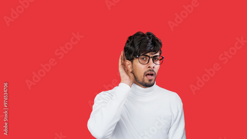 Gossip shock. Secret listening. Curious stunned guy in glasses eavesdropping whisper news isolated on red empty space background. photo