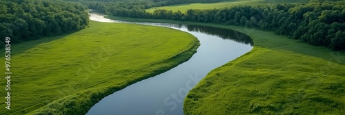 An aerial view of a winding river snaking through lush green fields, offering a serene and picturesque landscape. The water is calm and reflective, surrounded by vibrant greenery, creating a sense of