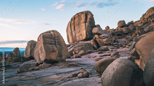 A photo of a rocky terrain with large boulders scattered across the landscape. The boulders vary in size and have unique shapes. Some of the boulders have grooves and patterns etched into them.