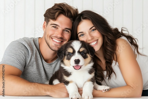Happy couple smiling with adorable puppy, close-up portrait of man, woman, and cute Australian Shepherd dog, family and pet love
