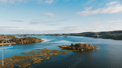 A photograph of a serene landscape from a high vantage point. The scene contains a vast body of water with a few small islands. The water is surrounded by lush greenery