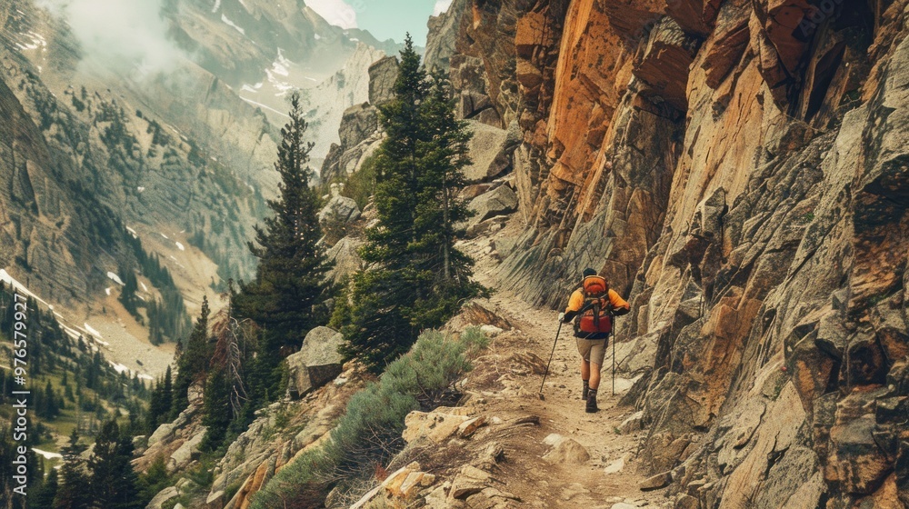 Obraz premium A hiker climbing a rugged trail in the Colorado Rockies