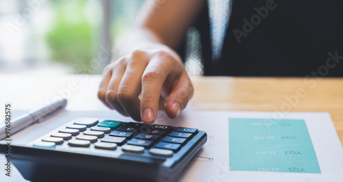 Accountant using calculator with financial documents on desk office.