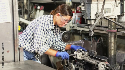 Portrait of female working with drilling machine on metal plate at a metallurgical plant photo