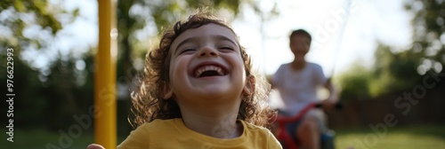 A toddler laughing heartily while on a swing, capturing the essence of happiness and carefree joy in a sunny park setting, highlighting innocence. photo