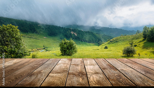 Empty wooden table with grassy field trees, hillside, and rain background