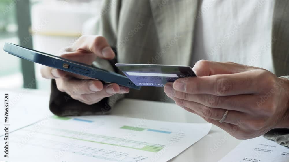 Asian male holding credit card and using smartphone for online payment