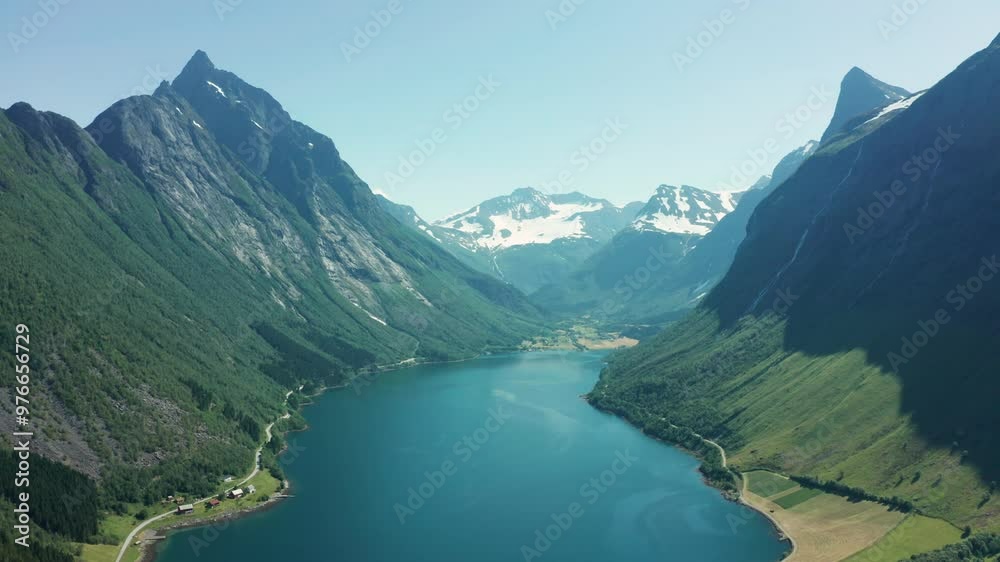 Panoramic aerial view of a deep blue fjord surrounded by towering mountains and green valleys in Norway. Panoramic aerial view of a deep blue fjord surrounded by towering mountains and green valleys in Norway.