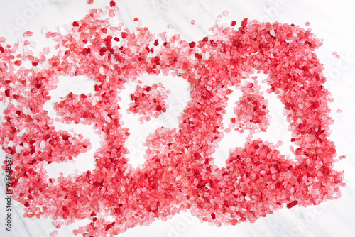 Red salt crystals are scattered on a white marble surface as a SPA word. The salt crystals are a beautiful pink color and have a natural, earthy feel