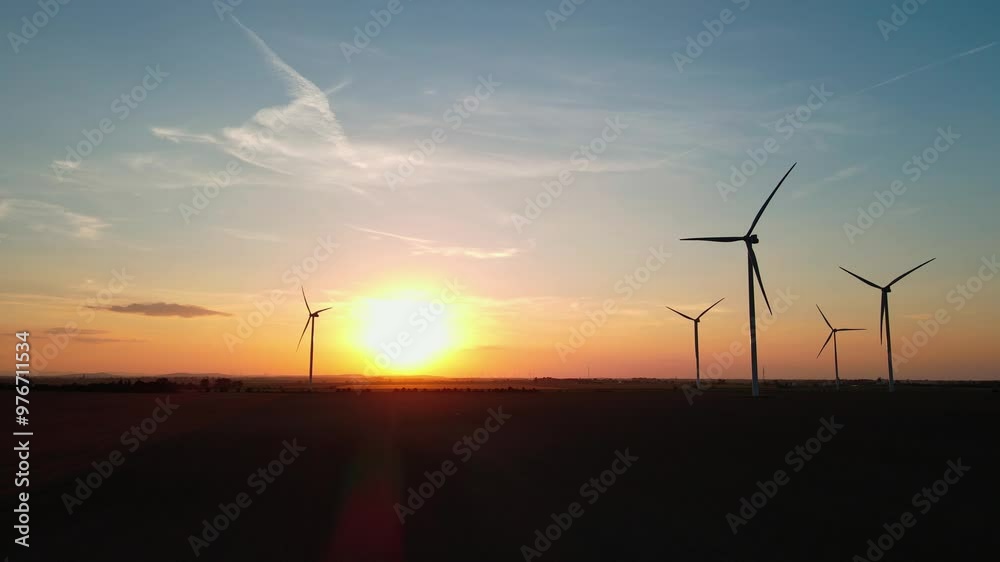 Silhouetted wind turbines in countryside landscape during sunset. Wind power plant generating clean energy. Concept of renewable and sustainable energy Silhouetted wind turbines in countryside landscape during sunset. Wind power plant generating clean energy. Concept of renewable and sustainable energy