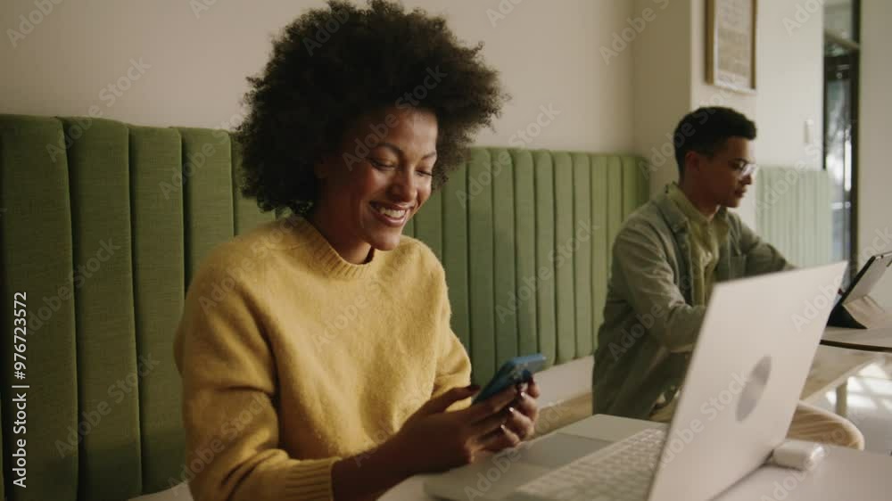 Mixed race woman laughing while typing on her phone Mixed race woman laughing while typing on her phone