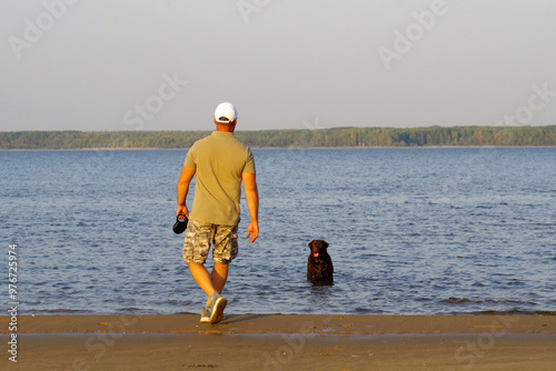 Caucasian mature man with a labrador by the river. pet enjoys water treatments. a dog walk. photo