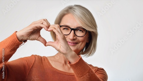 woman with glasses,Mature woman wears eyeglasses looking at camera through joined fingers showing heart symbol,