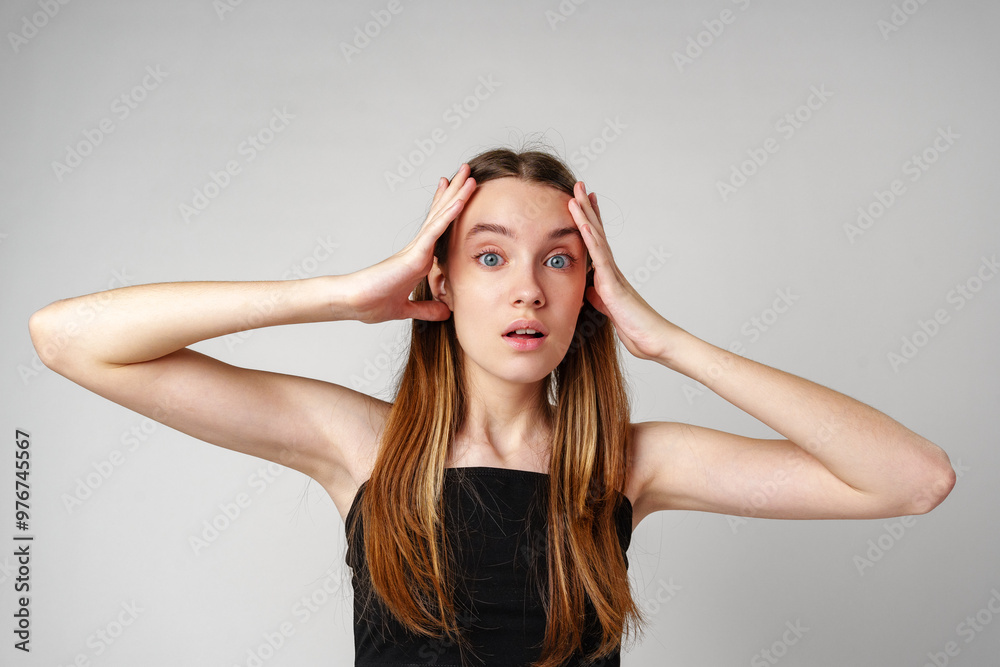 Young Woman With Long Brown Hair Holds Her Head in Shock Young Woman With Long Brown Hair Holds Her Head in Shock