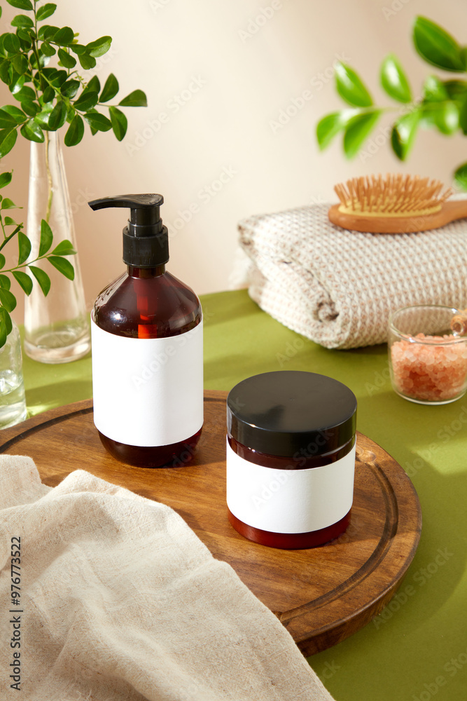 The image showcases an amber glass pump bottle and a black jar with blank labels, surrounded by a wooden cutting board, a white towel, pink salt bowl, and greenery, perfect for beauty product ads. The image showcases an amber glass pump bottle and a black jar with blank labels, surrounded by a wooden cutting board, a white towel, pink salt bowl, and greenery, perfect for beauty product ads.